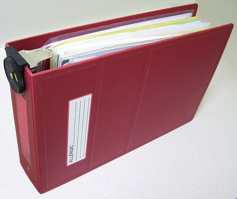 A red binder with papers in it.